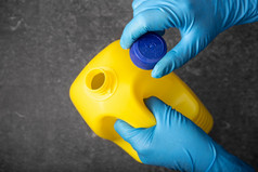 人类手保护手套开放黄色的漂白剂瓶消毒概念