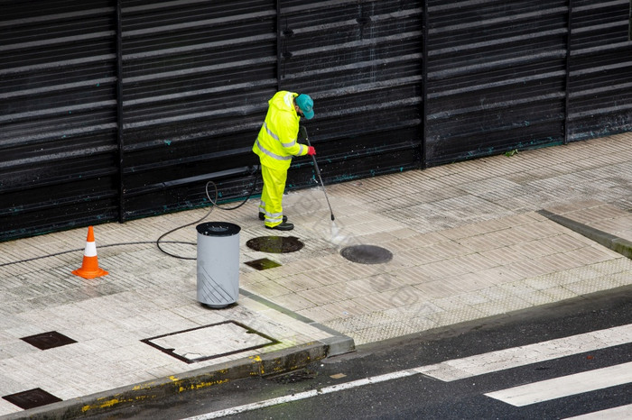 清洁工工人清洁街人行道上与高压力水飞机机多雨的一天复制空间