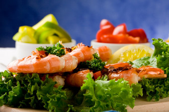 照片美味的<strong>烤虾</strong>在生菜床上与意大利辣香肠在蓝色的背景