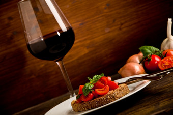 照片美味的意式烤面包片开胃菜与红色的酒玻璃木表格