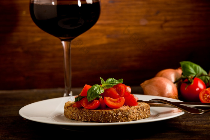 照片美味的意式烤面包片开胃菜与红色的酒玻璃木表格