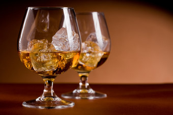 照片美味的玻璃白兰地威士忌与冰多维数据集棕色（的）背景