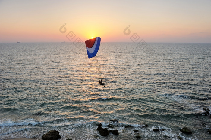 动力跳伞动力滑翔伞飞行在的海日落天空背景