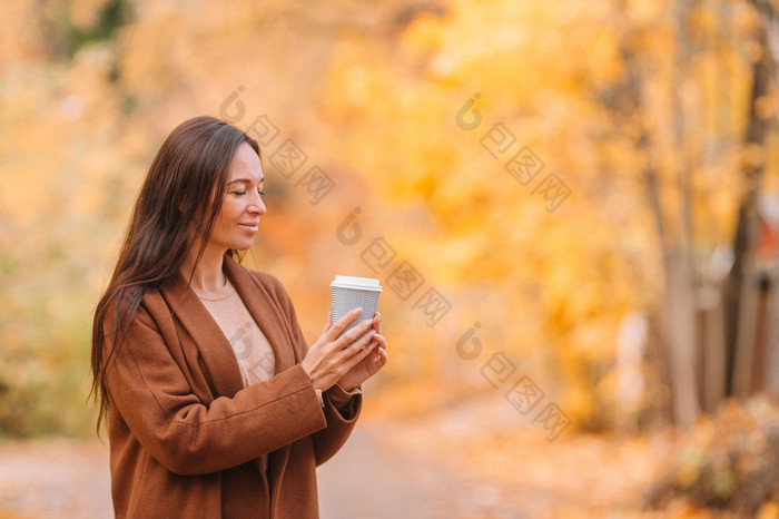 快乐女人喝咖啡秋天公园下秋天树叶金秋天公园秋天概念美丽的女人喝咖啡秋天公园下秋天树叶