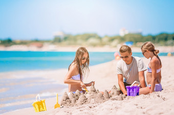 家庭爸爸和孩子们玩与<strong>沙子</strong>热带海滩父亲和孩子们使<strong>沙子城堡</strong>热带海滩家庭玩与海滩玩具
