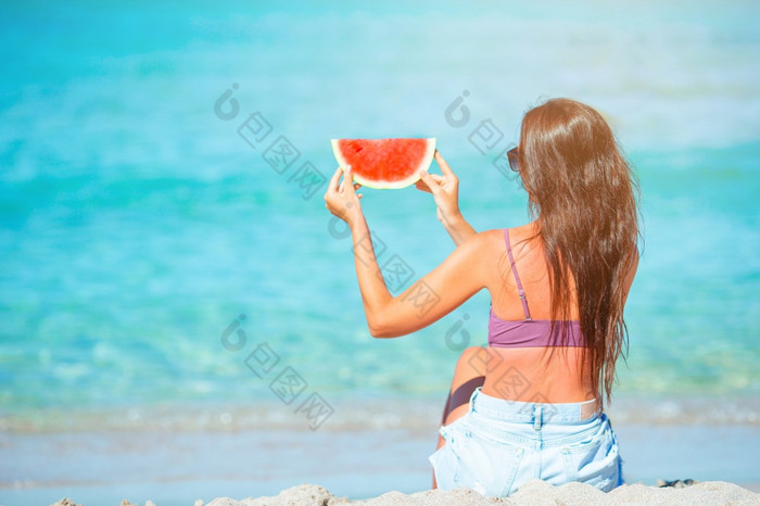 女人放松的海滩与片西瓜她的手快乐女孩有有趣的的海滩和吃西瓜