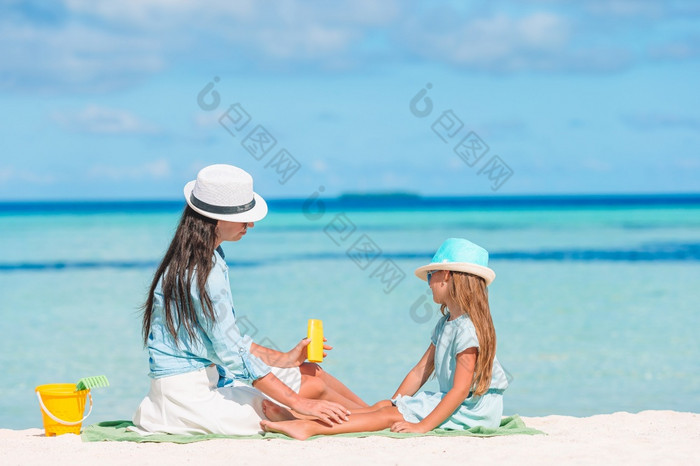 妈妈。应用太阳奶油她的孩子太阳保护的海滩年轻的妈妈。应用太阳奶油女儿鼻子的海滩太阳保护