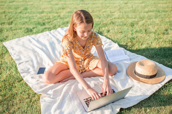 小女孩使用移动PC研究在户外的公园小女孩在户外的公园与电脑