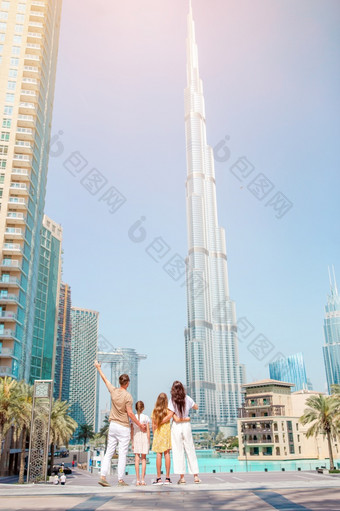 家庭四个与摩天大楼的背景迪拜阿联酋航空公司视图从后面快乐家庭走迪拜与摩天大楼的背景