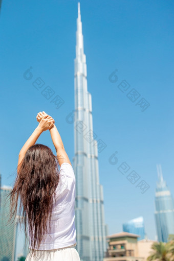 肖像美丽的女人走迪拜与摩天大楼的背景视图从后面快乐女人走迪拜与摩天大楼的背景