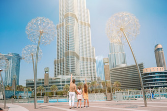 家庭迪拜与摩天大楼的背景视图从后面快乐家庭走迪拜与迪拜塔哈利法塔摩天大楼的背景