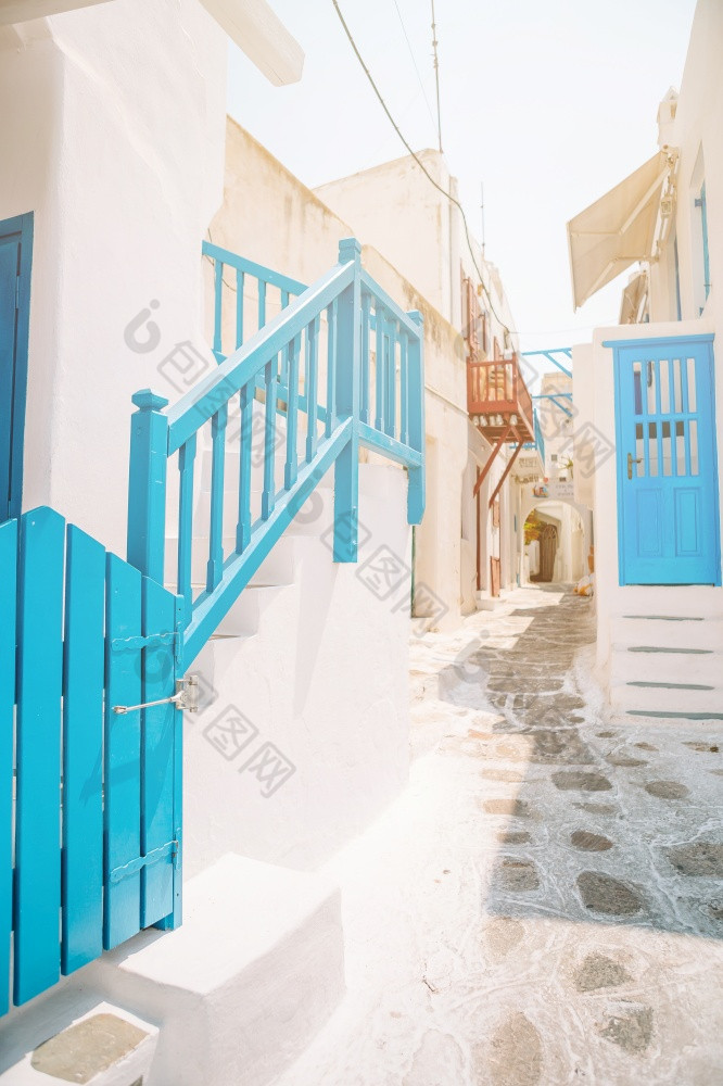 的狭窄的街道希腊岛与阳台楼梯和花美丽的体系结构建筑外与基克拉迪群岛的风格的狭窄的街道的岛与蓝色的阳台楼梯和花