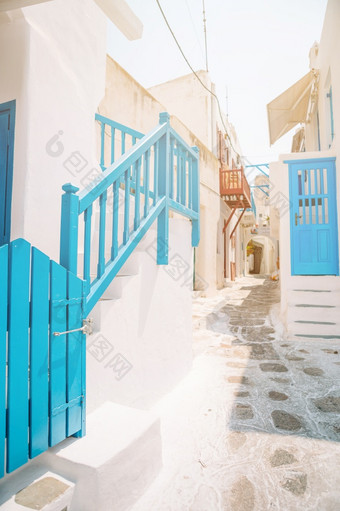 的狭窄的<strong>街道</strong>希腊岛与阳台楼梯和花美丽的体系结构建筑外与基克拉迪群岛的风格的狭窄的<strong>街道</strong>的岛与蓝色的阳台楼梯和花