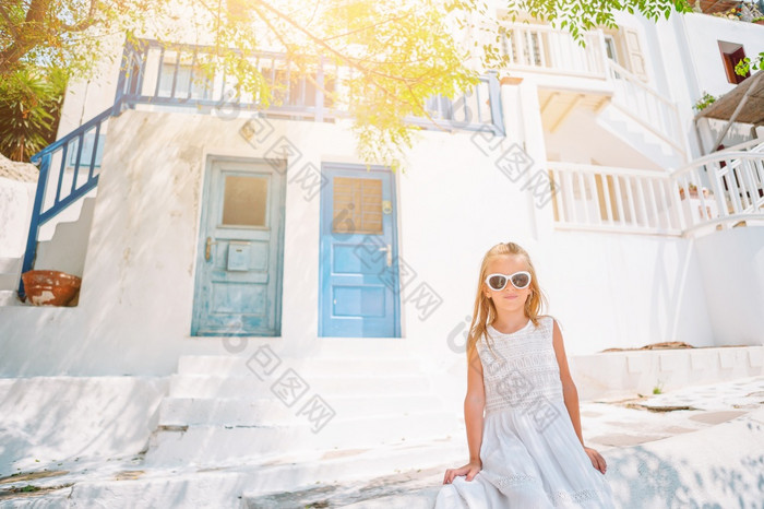 小可爱的女孩衣服在户外老街道米克诺斯孩子街典型的希腊传统的村与白色墙和色彩斑斓的门米克诺斯岛希腊小可爱的女孩衣服在户外老街道米克诺斯