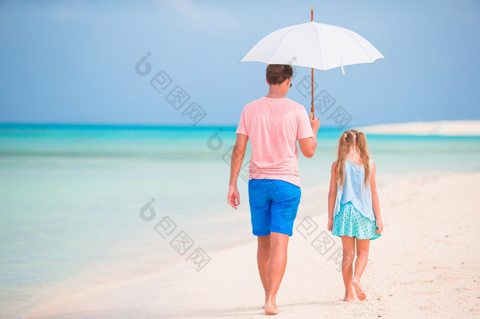 父亲和小女儿的海滩与伞隐藏从太阳年轻的父亲和他的小女儿走下伞白色沙子海滩