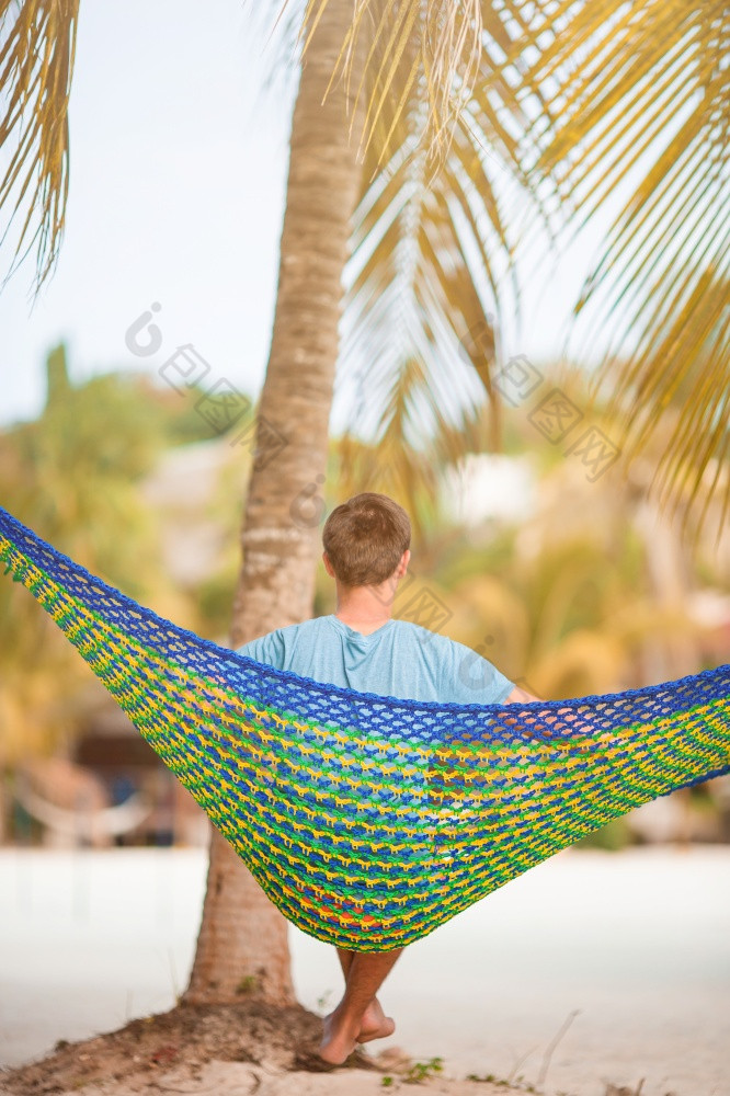 年轻的男人。放松吊床热带海滩懒惰的时间男人。他吊床夏天一天