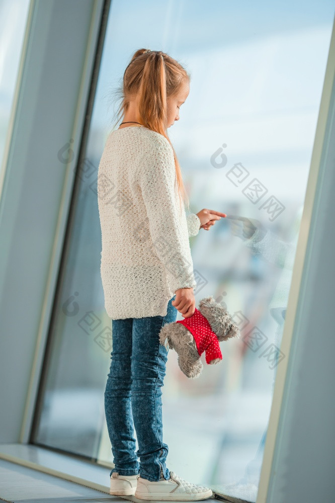 小女孩与泰迪熊玩具机场附近大窗口看为大飞机小女孩机场附近大窗口而等待为登机