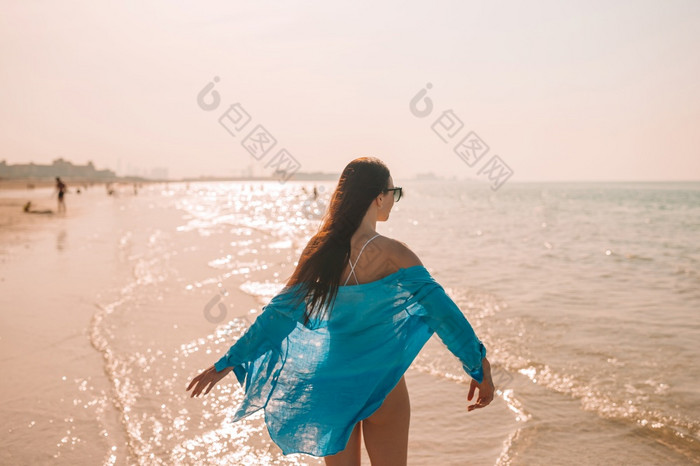 年轻的美丽的女人放松的海滩回来视图快乐女孩他和蓝色的衬衫女人铺设的海滩享受夏天假期看的海