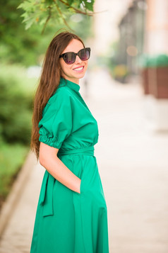 年轻的女人走在户外的的城市年轻的女人绿色衣服的城市