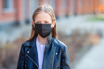 小孩子穿面具为防止病毒在户外保护对冠状病毒和抓手女孩穿面具保护对冠状病毒和抓手