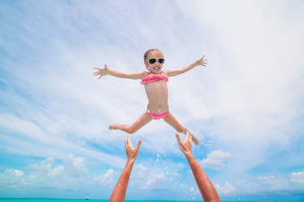 快乐父亲和他的可爱的小女儿玩在一起小女孩和快乐爸爸有有趣的在海滩假期