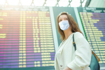 女人穿面具为防止病毒与行李国际机场保护对冠状病毒和抓手年轻的旅游女人与行李国际机场