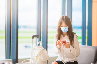 女人穿面具为防止病毒与行李国际机场保护对冠状病毒和抓手年轻的旅游女人与行李国际机场