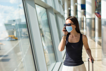 女人穿面具为防止病毒与行李<strong>国际机场</strong>保护对冠状病毒和抓手年轻的旅游女人与行李<strong>国际机场</strong>