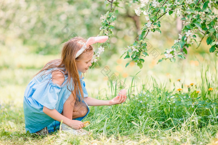 可爱的小女孩盛开的苹果树花园搜索复活节鸡蛋可爱的小女孩盛开的苹果花园美丽的春天一天