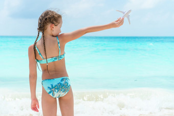 快乐小女孩与玩具飞机手白色桑迪海滩孩子玩与玩具的海滩快乐小女孩与玩具飞机手白色桑迪海滩
