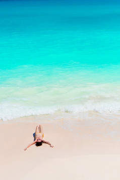 年轻的女人享受的太阳日光浴完美的绿松石海洋白色海滩年轻的女人享受的太阳日光浴完美的绿松石海洋