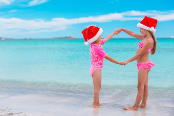 <strong>小</strong>可爱的女孩圣诞老人帽子有有趣的阿纳德愚弄圣诞节的海滩<strong>小</strong>可爱的女孩圣诞老人帽子在海滩圣诞节假期有有趣的在一起