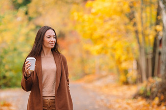 快乐女人喝咖啡秋天公园下秋天树叶金秋天公园秋天概念美丽的女人喝咖啡秋天公园下秋天树叶