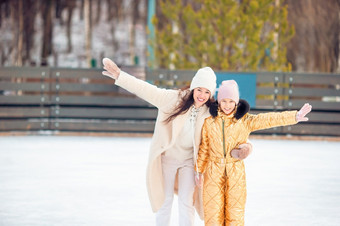 小可爱的女孩与她的妈妈。滑冰溜冰场家庭冬天有趣的小可爱的女孩与她的妈妈。滑冰溜冰场