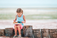 小女孩阅读书在热带白色海滩小可爱的女孩阅读书在热带白色海滩