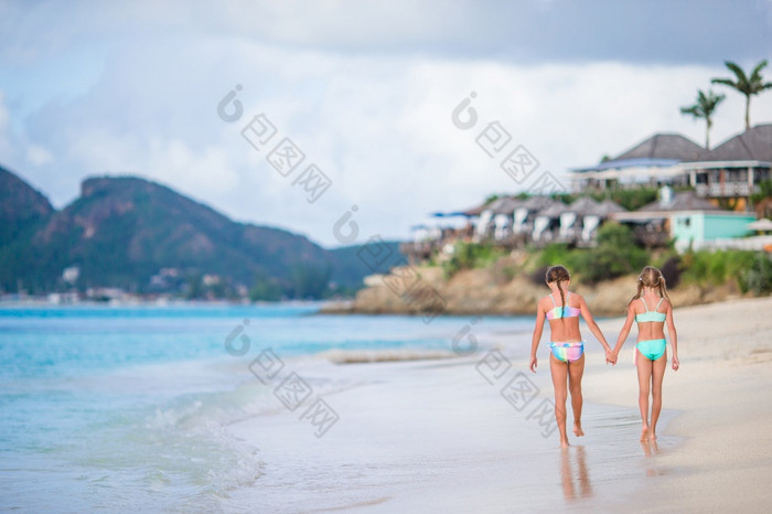 小女孩有有趣的热带海滩玩在一起浅水可爱的小姐妹海滩在夏天假期两个小快乐女孩有很多有趣的热带海滩玩在一起