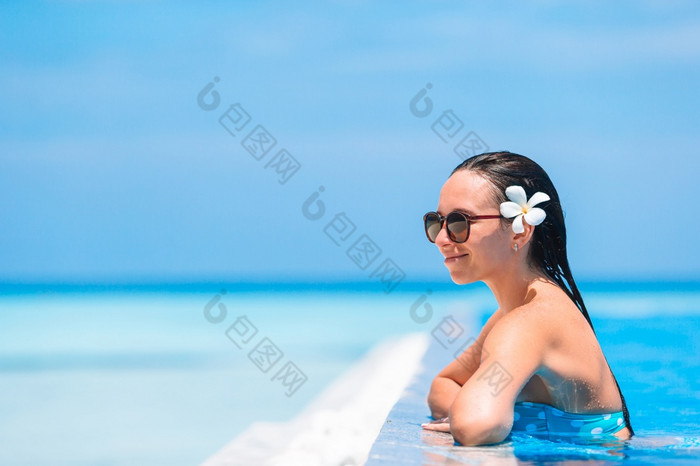 年轻的美丽的女人享受夏天假期∞奢侈品游泳池年轻的美丽的女人享受夏天假期奢侈品游泳池