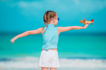 快乐小女孩与玩具飞机手白色桑迪海滩孩子玩与玩具的海滩快乐小女孩与玩具飞机手白色桑迪海滩