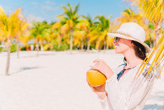 快乐年轻的女人喝椰子牛奶的海滩假期快乐年轻的女人喝椰子牛奶海滩