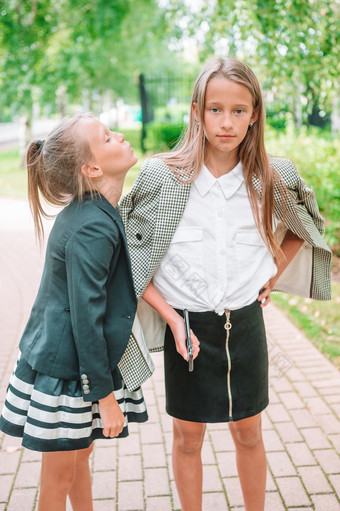 两个可爱的小女孩摆姿势前面他们的学校可爱的小孩子们感觉非常兴奋关于会回来学校两个可爱的铣削小女孩摆姿势前面他们的学校