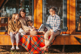 快乐家庭坐着的阳台他们的房子秋天美丽的家庭走秋天温暖的一天