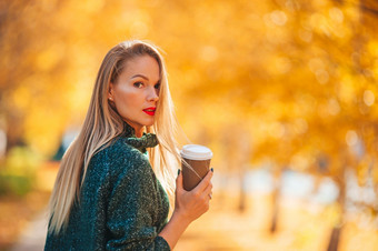 美丽的女人与咖啡秋天公园下秋天树叶温暖的一天秋天概念美丽的女人秋天公园下秋天树叶