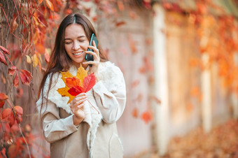 美丽的女人会说话的电话秋天公园下秋天树叶金秋天公园和女人的走美丽的女人秋天公园下秋天树叶