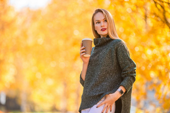 肖像美丽的女人与热咖啡秋天公园下秋天树叶秋天概念美丽的女人喝咖啡秋天公园下秋天树叶