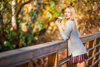 美丽的女人秋天公园下秋天树叶温暖的一天秋天概念美丽的女人喝咖啡秋天公园下秋天树叶