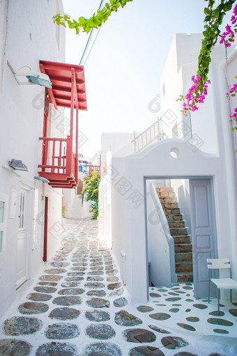 的狭窄的街道的岛与蓝色的阳台楼梯和花希腊美丽的体系结构建筑外与基克拉迪群岛的风格的狭窄的街道的岛与蓝色的阳台楼梯和花希腊