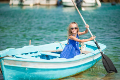 小女孩蓝色的船的海湾希腊小孩子享受游泳的小船小女孩蓝色的船的海湾希腊