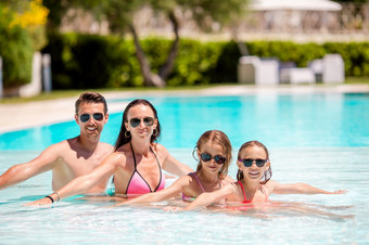家庭假期户外游泳池年轻的家庭与两<strong>个</strong>孩子们享受夏天假期户外池