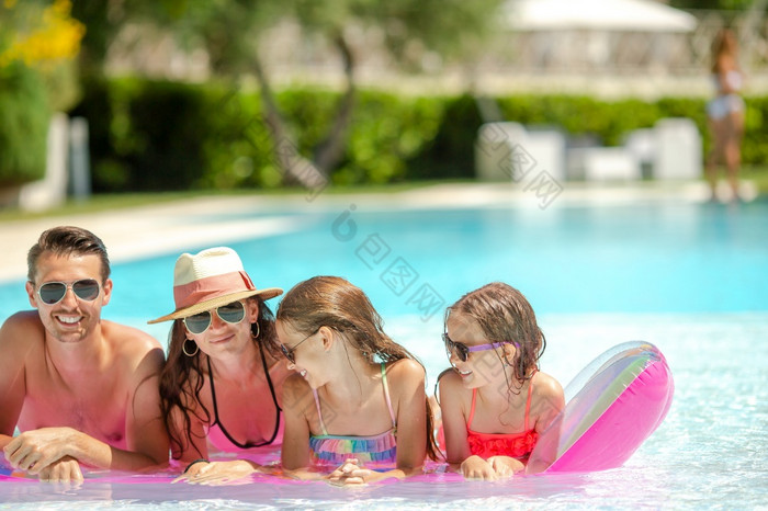 家庭假期户外游泳池年轻的家庭与两个孩子们享受夏天假期户外池