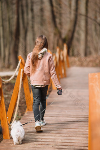 小快乐女孩走与白色小狗在户外早期春天小女孩与白色小狗小狗的手女孩